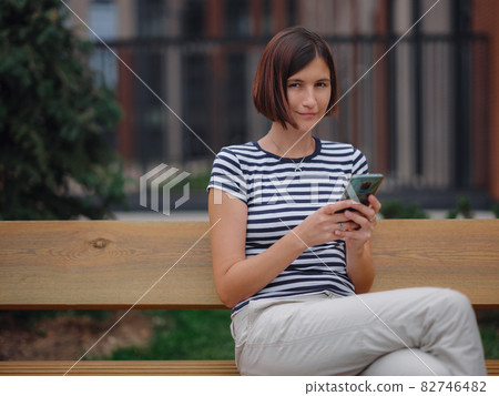 Smiling woman using mobile phone in the street Smiling woman using mobile phone in the street 82746482