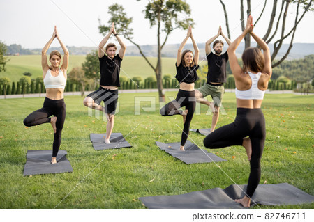 People practicing yoga on fitness mats on lawn People practicing yoga on fitness mats on lawn 82746711