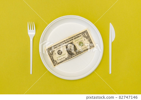 Top view of disposable cutlery and plate with dollar bill 82747146