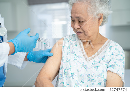 Elderly Asian senior woman wearing face mask getting covid-19 or coronavirus vaccine by doctor make injection. Elderly Asian senior woman wearing face mask getting covid-19 or coronavirus vaccine by doctor make injection. 82747774