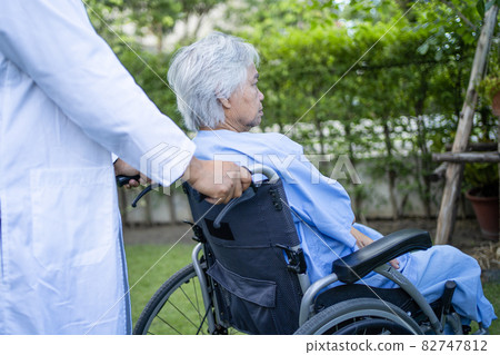 Doctor help and care Asian senior or elderly old lady woman patient sitting on wheelchair at park in nursing hospital ward, healthy strong medical concept. 82747812