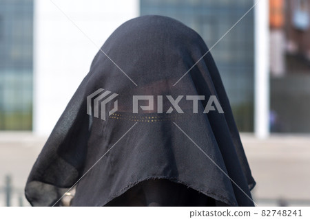 Portrait of a Muslim woman in national clothes covering her face in a European city Portrait of a Muslim woman in national clothes covering her face in a European city 82748241