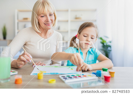 Granny and granddaughter drawing with paint at home 82748583