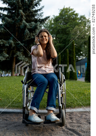 Disabled woman in wheelchair listens to music Disabled woman in wheelchair listens to music 82749288