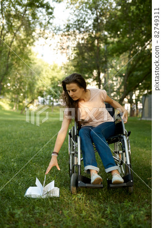 Disabled woman in wheelchair tries to pick up book Disabled woman in wheelchair tries to pick up book 82749311