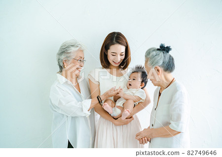 Mom holding a baby and two senior women 82749646