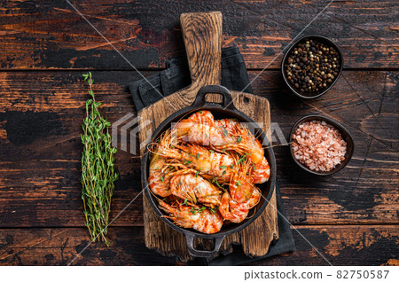 Cooking Greenland Shrimps Prawns in a pan with thyme and rosemary. Dark wooden background. Top view Cooking Greenland Shrimps Prawns in a pan with thyme and rosemary. Dark wooden background. Top view 82750587