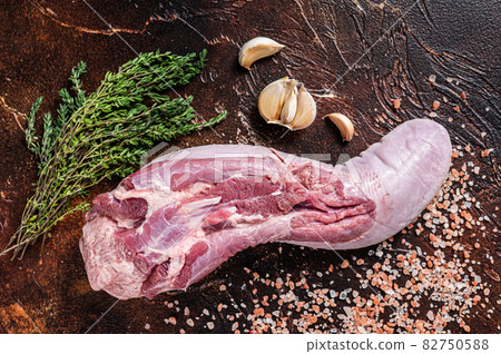 Raw beef tongue on kitchen table with herbs. Dark background. Top view Raw beef tongue on kitchen table with herbs. Dark background. Top view 82750588