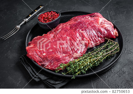 Flank or flap raw beef steak on plate with thyme. Black background. Top view Flank or flap raw beef steak on plate with thyme. Black background. Top view 82750653