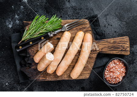 Roasted chicken and turkey sausages on a wooden board. Black background. Top view 82750724