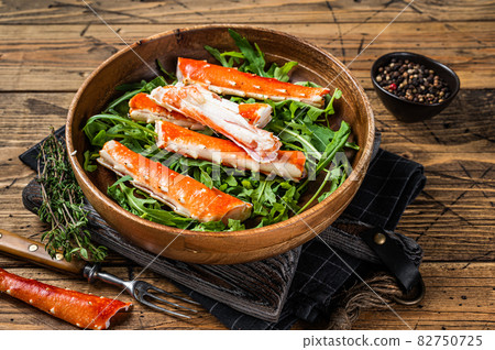 Salad with King Crab legs in a wooden plate. wooden background. Top view Salad with King Crab legs in a wooden plate. wooden background. Top view 82750725