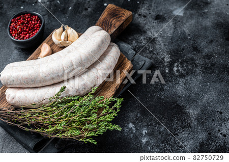 Raw Munich white sausage weisswurst on wooden board. Black background. Top view. Copy space Raw Munich white sausage weisswurst on wooden board. Black background. Top view. Copy space 82750729