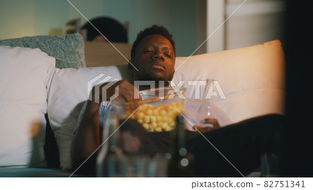 Sleepy black man watching match at night 82751341