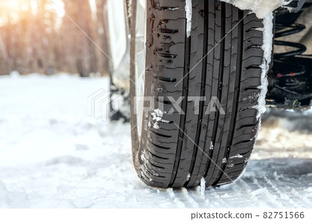 Close-up detail view of car wheel with unsafe summer tread tire during driving through slippery snow road at winter season. Danger traffic accident collision risk. Seasonal tyre switch concept 82751566