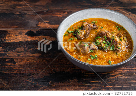 Kharcho beef meat soup with rice, tomatoes and spices in a bowl. Dark wooden background. Top view. Copy space Kharcho beef meat soup with rice, tomatoes and spices in a bowl. Dark wooden background. Top view. Copy space 82751735