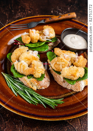 Sandwichs with Fried Shrimps, Prawns, spinach and chard salad on a rustic plate. Dark background. Top view 82751772