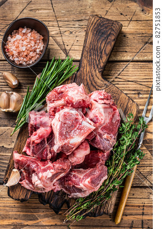 Raw beef meat diced for stew with bone. wooden background. Top view Raw beef meat diced for stew with bone. wooden background. Top view 82751853