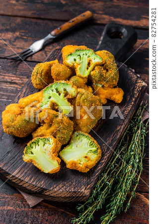 Crumbed broccoli steaks on a wooden board. Dark wooden background. Top view 82754281