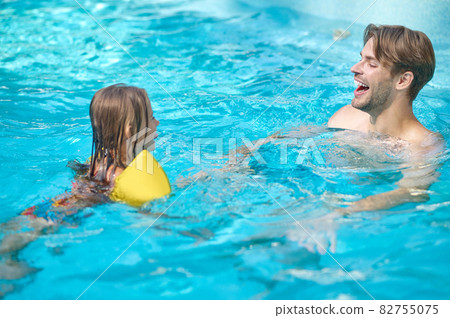 A young man and his kid swimming in the pool and looking enjoyed 82755075