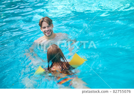 A young man and his kid swimming in the pool and looking enjoyed 82755076