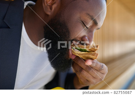 A man sitting on the bench and having lunch 82755087
