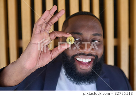 A bearded dark-skinned man holding a bitcoin A bearded dark-skinned man holding a bitcoin 82755118