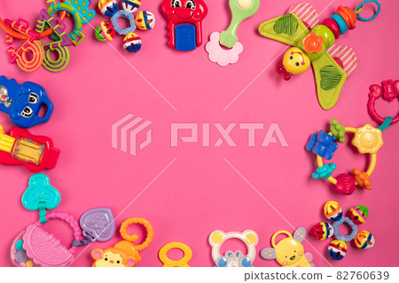Children's rattle from plastic on a pink background. Top view 82760639