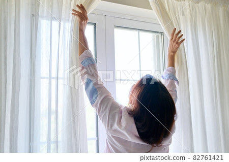 Close-up of woman's hand opening and closing light translucent curtains 82761421
