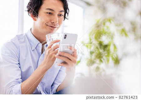 A young man looking at a smartphone screen with a smile 82761423