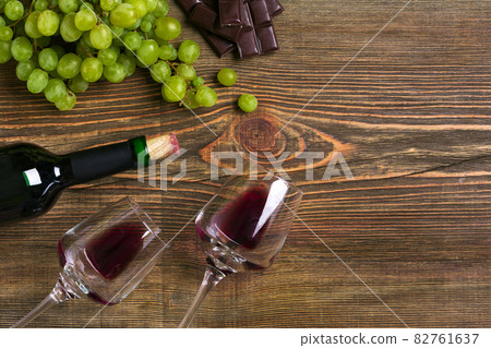 Two glasses, bottle of red wine and grape on a wooden table 82761637