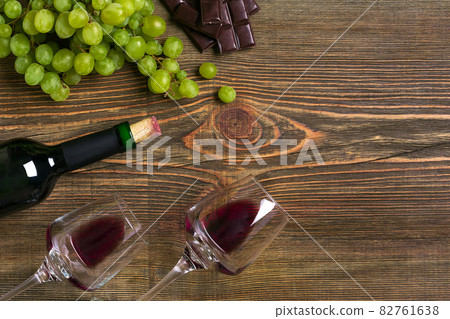Two glasses, bottle of red wine and grape on a wooden table Two glasses, bottle of red wine and grape on a wooden table 82761638
