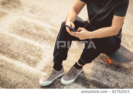 Woman skateboarder using smartphone  outdoors 82762021