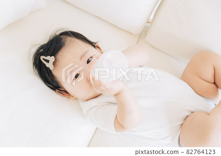Baby drinking milk from a bottle Baby drinking milk from a bottle 82764123
