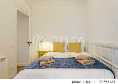 Interior of touristic bedroom. Yellow pillows on bed with towels. An apartment ready for booking by tourists 82765183