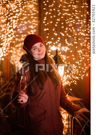 Christmas holiday celebration. Girl drinking champagne over holiday glowing golden background. Christmas holiday celebration. Girl drinking champagne over holiday glowing golden background. 82765921