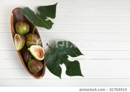 Figs in a wooden plate with leaves 82768910