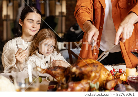 Close-up happy young men and women, married couple celebrate Thanksgiving day. Family dinner with roasted turkey Close-up happy young men and women, married couple celebrate Thanksgiving day. Family dinner with roasted turkey 82769361