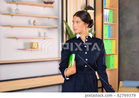 Portrait of a girl in a school uniform with a book in her hands. The child reads a textbook. Preparing a schoolgirl for a school lesson or exam 82769379