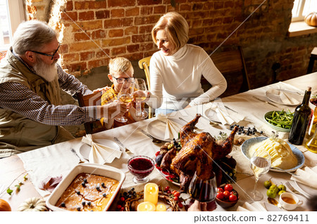 Happy grandfather, grandmother and grandson celebrate Thanksgiving day at home, indoors. 82769411
