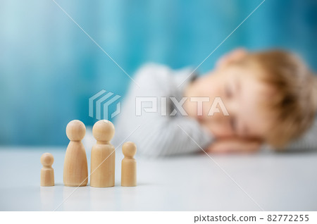 Child with wooden figures of the family on the blue background 82772255
