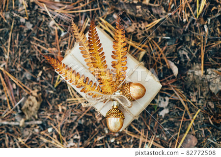 A gift wrapped in craft paper and decorated with dried fern leaves and glass acorns. A gift wrapped in craft paper and decorated with dried fern leaves and glass acorns. 82772508
