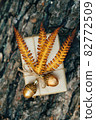 A gift wrapped in craft paper and decorated with dried fern leaves and glass acorns. 82772509