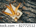 A gift wrapped in craft paper and decorated with dried fern leaves and glass acorns. 82772512