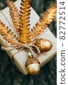 A gift wrapped in craft paper and decorated with dried fern leaves and glass acorns. 82772514