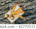 A gift wrapped in craft paper and decorated with dried fern leaves and glass acorns. 82772515