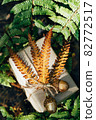 A gift wrapped in craft paper and decorated with dried fern leaves and glass acorns. 82772517