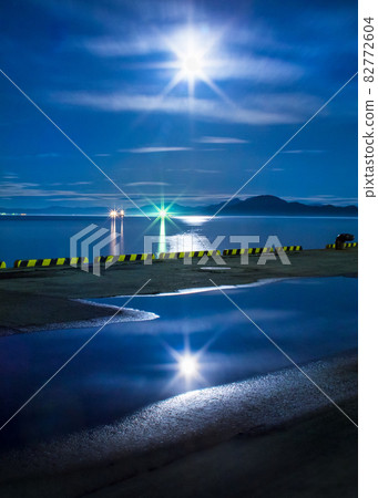 It is the harbor scenery of moonlight. The moon is shining big. It is a landscape at a time close to midnight. 82772604