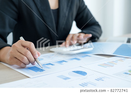 The hand of an accountant woman is analyzing and calculating the financial graph showing the results in the office The hand of an accountant woman is analyzing and calculating the financial graph showing the results in the office 82772741