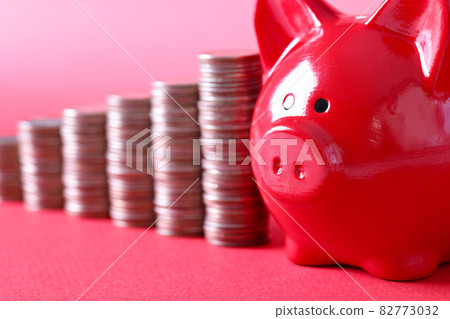 Red pig piggy bank and stacks of coins stand on red background Red pig piggy bank and stacks of coins stand on red background 82773032
