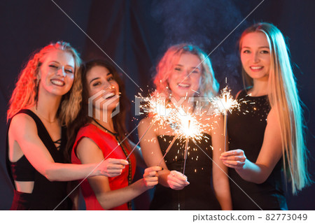 Birthday party, new year and holidays concept - Group of female friends celebrating holding sparklers Birthday party, new year and holidays concept - Group of female friends celebrating holding sparklers 82773049
